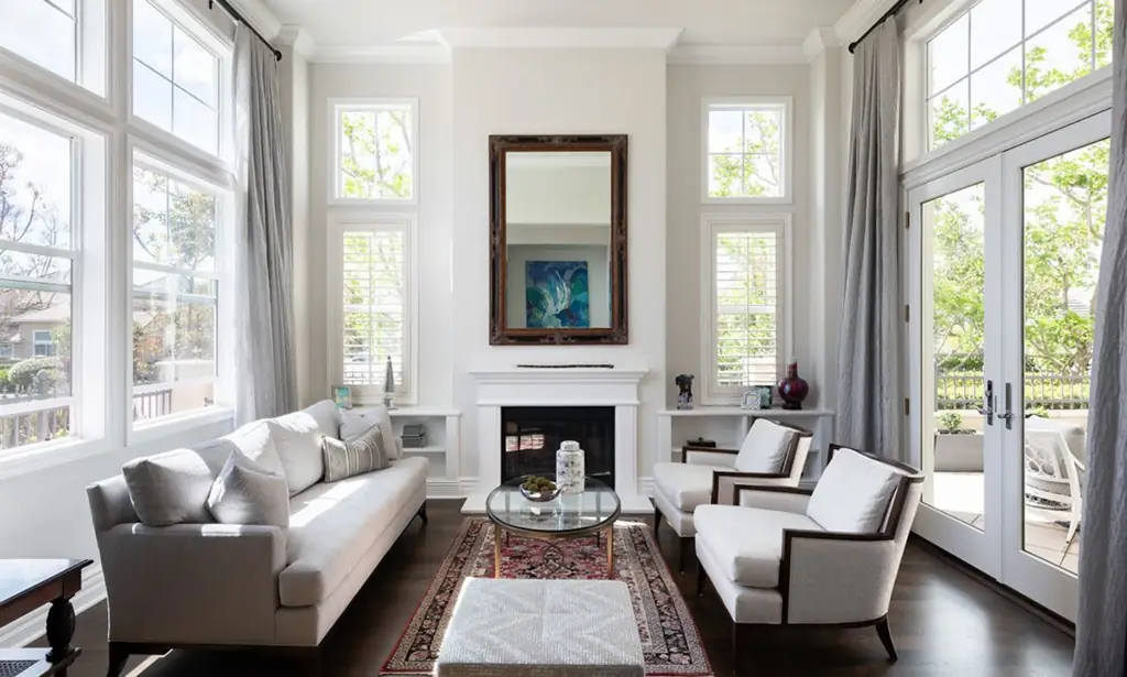 A bright double-height living room with a fireplace and French doors onto a terrace